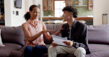 Afro-Amerikan anne ve oğlu kanepenin üzerinde mektup okuyor ve evde iyi haberleri kutluyorlar. Aile, iletişim, sürpriz, neşe, sevgi, ev, birliktelik