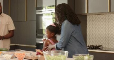 Modern mutfakta çeşitli aileler birlikte yemek pişiriyor, evde taze sebzeleri neşeyle hazırlıyorlar. Yemek hazırlama, bağ kurma, aşçılık, takım çalışması, birliktelik