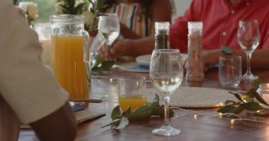 Kadın elinde şarap kadehi tutuyor, gülümsüyor ve dışarıda çeşitli ailelerle konuşuyor. Kutlama, şenlik, toplanma, sohbet, boş zaman, birliktelik