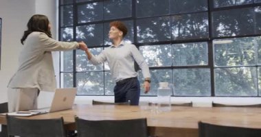 Çeşitli meslektaşlar modern ofis toplantı odasında dizüstü bilgisayar kullanırken projeyi tartışıyorlar. İşbirliği, takım çalışması, beyin fırtınası, tartışma, teknoloji, işyeri