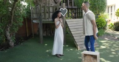 Bahçede romantik bir evlilik teklifi, yüzükle diz çökmüş bir adam, sevinçle şaşırmış bir kadın, kopyalama alanı. Nişan, romantizm, aşk, bağlılık, farklı çiftler, bahçede