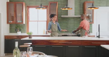 Çeşitli çiftler modern mutfakta birlikte yemek pişiriyor, evde yemek hazırlıyor ve kaynaşıyorlar. Mutfak