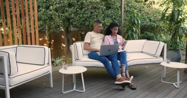 Verandada, çeşitli çiftler dizüstü bilgisayar ve akıllı telefon kullanıyorlar, bahçede birlikte dinleniyorlar. Teknoloji, rahatlama, cihazlar, iletişim, bağlantı, yaşam tarzı