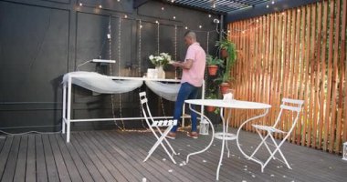 Romantik bir ortam yaratmak, terasta yürüyen bir adam, ışık ve masa. ambiyans, akşam, bahçede, farklı çiftler, zarafet, aydınlanma