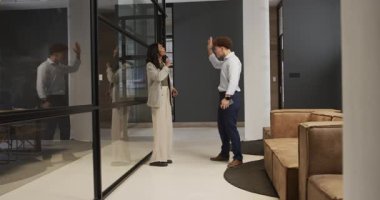 Başarıyı kutlayan çeşitli meslektaşlar modern ofis ortamında coşkuyla beşlik çakıyor. İş, takım çalışması, işbirliği, başarı, motivasyon