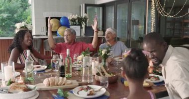 Çeşitli aileler yemek masasının etrafında kadehler kaldırıyor, keyifli toplantıları evde kutluyorlar. Kutlama, akşam yemeği, birliktelik, tost, mutluluk, yaşam tarzı