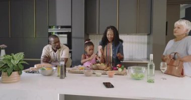 Üç nesil modern mutfakta birlikte yemek hazırlıyor, neşeli anları paylaşıyorlar. Çeşitli aile, birliktelik, yemek pişirme, çok nesilli, bağlanma, yaşam tarzı