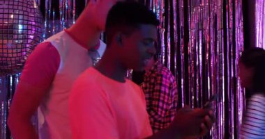 Çeşitli arkadaşlar süs eşyası takıyor, ışıklandırıyor, doğum günü pastasını salonda sürpriz yapmak için taşıyor. Kutlama, parti, gece hayatı, coşku, arkadaşlık, birleşme, eğlence