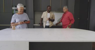 Üç nesil modern mutfakta kaliteli vakit geçirmenin keyfini çıkarıyor, kahkahalarımızı paylaşıyorlar. çeşitli aile, çok nesilli, bağlanma, birliktelik, mutluluk, ev