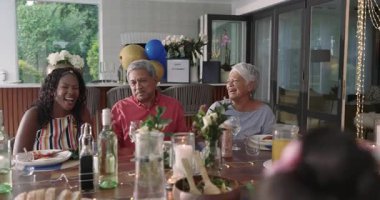 Çeşitli aileler birlikte akşam yemeğinin tadını çıkarıyor, hikayelerini ve gülüşünü evde, şenlikli bir toplantıda paylaşıyorlar. Kutlama, birliktelik, hikaye anlatma, mutluluk, bağ kurma, gelenek