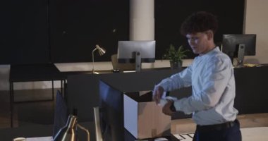 Genç profesyonel ofis eşyalarını kutuya koyup kariyer değişimine hazırlanıyor. Taşınma, kariyer değişikliği, istihdam, işyeri, hazırlık, masa