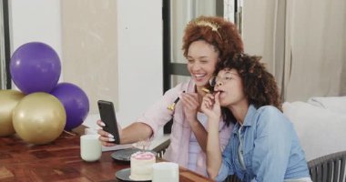 Eşcinsel çeşitlilikte lezbiyen bir çift doğum gününü kutluyor evde pasta ve balonlarla selfie çekiyorlar. Kutlama, lgbtq, çeşitlilik, teknoloji, parti, mutluluk