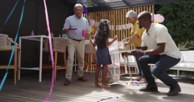 Büyükannem neşeli bir şekilde çeşitli ailelerle güneşli terasta doğum günü süsleri hazırlıyor. Kutlama, parti, açık hava, mutluluk, toplanma, nesiller boyu