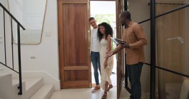 Çeşitli çiftler ev girişinde birbirlerini selamlıyorlar, gülümsüyorlar ve tablet tutuyorlar. Arkadaşlık, misafirperverlik, birliktelik, teknoloji, sosyalleşme.