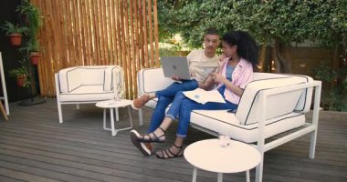 Çeşitli çiftler avluda dizüstü bilgisayar kullanıyor ve belgeleri tartışıyorlar. takım çalışması, tartışma, teknoloji, iletişim, işbirliği, yaşam tarzı