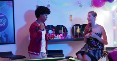 Farklı arkadaşlar doğum gününü kutlarken disko salonunda pastayı aydınlatan maytaplara gülüyorlar. Şenlik, kutlama, gece hayatı, canlı, sosyal, neşeli, retro