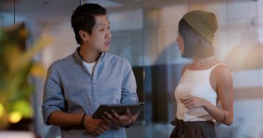 Modern ofisteki çeşitli iş arkadaşlarıyla konuşurken gülümseyen gözlüklü Asyalı kadın. İş, takım çalışması, işbirliği, iletişim, meslek, tartışma