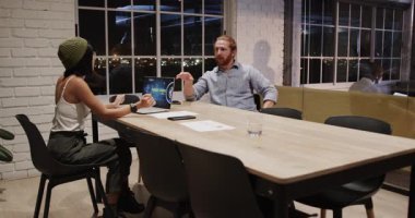 Çeşitli meslektaşlar ofis masasında dizüstü bilgisayar ve belgeler kullanarak projeyi tartışıyor. İşbirliği, takım çalışması, beyin fırtınası, toplantı, iş, iletişim