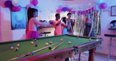 Çeşitli arkadaşlar doğum günü alkışlarını duyuyorlar onur konuğuna sarılıyorlar, evde bilardo masası oyunu hazırlıyorlar. Kutlama, yoldaşlık, eğlence, kırsal, iyimser, eğlence, çeşitlilik