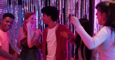 Farklı arkadaşlar disko balosunun altında pasta ve balonlarla dans ediyorlar. Kutlama, gece hayatı, eğlence, parti, coşku, canlılık, sosyalleşme