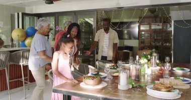 Çeşitli aileler yemek masasının etrafında toplanıyor, evde yemek yiyor ve gülüyor. Beraberlik, kutlama, mutluluk, gelenek, neşe, bağ