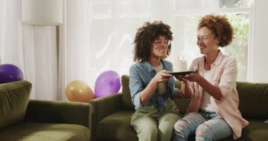 Evlerinde kutlama yapıyorlar, neşeli lezbiyen çift rahat oturma odasında pasta kesiyorlar. Kutlama, birliktelik, mutluluk, yaşam tarzı, tatlı, bağ