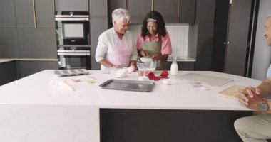 Büyükanne ve torun modern mutfakta birlikte yemek pişirirken gülüyorlar. Çeşit çeşit aile, kaynaşma, yemek pişirme, kahkaha, nesiller boyu