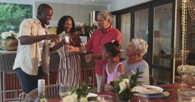 Çeşitli aileler birlikte akşam yemeğinin keyfini çıkarıyor, evde yemek masasının etrafında gülüşmeler ve hikayeler paylaşıyorlar. Beraberlik, kaynaşma, mutluluk, kutlama, toplanma, yemek zamanı