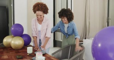 Eşcinsel çeşitlilikte lezbiyen bir çift evde pasta ve balonlarla birlikte gülüyor. Kutlama, mutluluk, birliktelik, aşk, ilişki, neşe