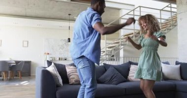 Modern çatı katındaki gri koltukta dans eden çift, metal merdiven korkuluklarıyla yastık fırlatıyorlar. Çağdaş, kutlama, neşe, zarafet, yaşam tarzı, iç mekan, canlı