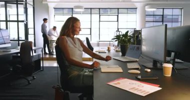 Modern ofisteki çeşitli meslektaşlar başarıyı kutluyor, gülümsüyor ve dizüstü bilgisayarın yanında alkışlıyorlar. Takım çalışması, işbirliği, iş, başarı, şirket, işyeri