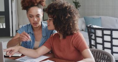 Eşcinsel çeşitlilikte lezbiyen çift evde çalışıyor, telefon görüşmeleri yaparken belgeleri tartışıyorlar. LGBTQ, ev ofisi, işbirliği, telekomünikasyon, evrak işleri, takım çalışması.