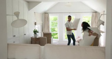 Çeşitli çiftler kutularını açıyor ve evdeki rahat oturma odasında yastıkları düzenliyorlar. Taşınma, taşıma, yerleşim, iç tasarım, yaşam tarzı, ev