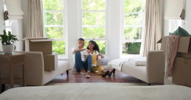 Çeşitli çiftler evlerinde, oturma odasında yerde otururken kutuları açıyor ve dizüstü bilgisayar kullanıyorlar. Taşınmak, taşınmak, birlikte eve gitmek.