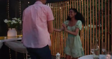 Çeşitli çiftler verandada, romantik yemek düzenleri ve ip ışıklarıyla neşeyle dans ediyorlar. Aşk, kutlama, mutluluk, akşam, dans, bahçede