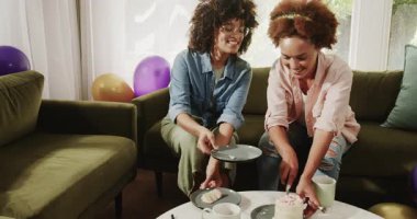 Farklı lezbiyen çiftler evlerinde rahat oturma odalarında kek ve kahvenin tadını çıkarıyorlar. tatlı, yaşam tarzı, içecek, rahatlama, ev, arkadaşlık