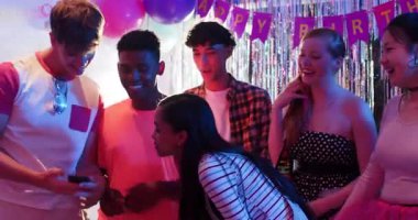 Çeşitli arkadaşlar doğum günü afişi altında evde selfie çekiyorlar disko topuyla dans edip içkilerini yudumluyorlar. Kutlama, arkadaşlık, parti, eğlence, canlı, neşeli, sosyalleşme