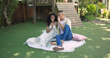 Çeşitli çiftler bahçede battaniyede pikniğin tadını çıkarıyor, gülümsüyor ve anı paylaşıyorlar. Romantik, birliktelik, doğa, rahatlık, bağ, sükunet