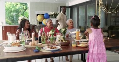 Çeşitli aileler birlikte akşam yemeğinin tadını çıkarıyorlar. İnsanlar evlerinde şenlik sofrasında su döküyorlar. Kutlama, yemek, yemek, toplanma, yemek, servis