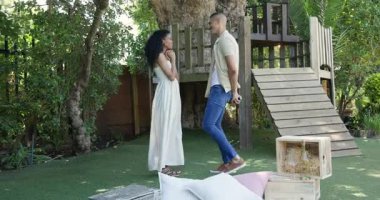 Erkek kadına bahçede evlenme teklif ediyor, hem gülümsüyor hem de neşeli bir anı kucaklıyor. Teklif, nişan, aşk, romantizm, farklı çiftler, mutluluk