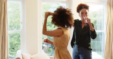 Çeşitli lezbiyen çiftler evde neşeyle dans ediyor, ellerinde şampanya bardakları ve sıcak bir gülümsemeyle. Kutlama, mutluluk, yaşam tarzı, romantizm, neşe, ilişki