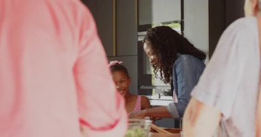 Mutfakta büyükannene sarılmak, torununun evde eğlenceli aile anlarını paylaşması. Beraberlik, sevgi, nesiller arası bağ, mutluluk, sıcaklık.