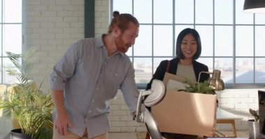 Ofisteki çeşitli meslektaşlar kutularını açarken ve çalışma alanını düzenlerken kahkahalar atıyorlar. İşbirliği, takım çalışması, yer değiştirme, iş, organizasyon, eğlence