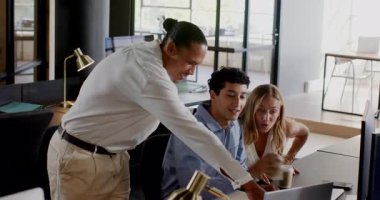 Çeşitli meslektaşlar ofis masasında iş birliği yapıyor, gülümsüyor ve dizüstü bilgisayarla projeyi tartışıyorlar. İşbirliği, takım çalışması, beyin fırtınası, iş, teknoloji, toplantı