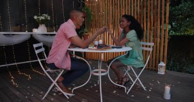 Bahçe avlusunda mum ışığında romantik bir akşam yemeğinde el ele tutuşan çeşitli çiftler. Aşk, aşk, ilişki, akşam yemeği, mum.