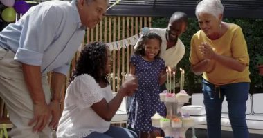 Farklı aileler doğum günlerini kutlarken genç bir kız keklerin üzerine mumlar üflüyor. Kutlama, mutluluk, çocukluk, gelenek, parti, toplanma