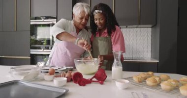 Kek pişirmek, büyükanne ve çocuğun modern mutfakta gülümsemesi. Çeşit çeşit aile, bağlılık, yemek pişirme, mutluluk, konforlu, çok nesilli