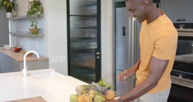 Yeşil elmalarla hokkabazlık yapan, afro-amerikan adam mutfak adasında ürünlerle dikilen, kopyalama alanı. Beslenme, sağlıklı yaşam tarzı, modern tasarım, ev yemeği, sağlık, tazelik, organik