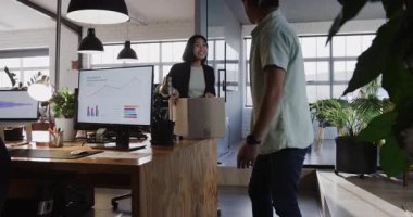 Meslektaşı modern ofise girerken Asyalı kadın bilgisayarda grafikleri analiz ediyor. İşbirliği, takım çalışması, veri analizi, iş dünyası, iş arkadaşları, üretkenlik