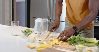 Ayakta duran Afrikalı Amerikalı adam mutfak adasında meyve püresi hazırlıyor blender tabanlı, kopyalama alanı var. Sağlık, beslenme, sağlık, aşçılık, yaşam tarzı, minimalist, enerjik